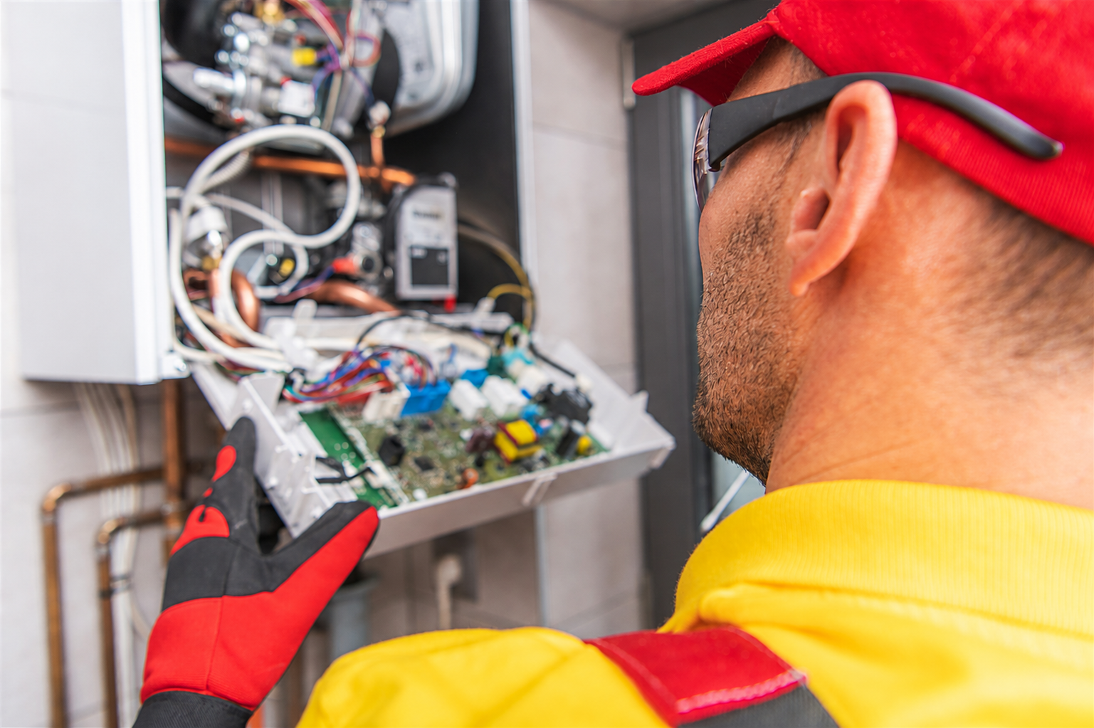Engineer inspecting and repairing a wall-mounted boiler